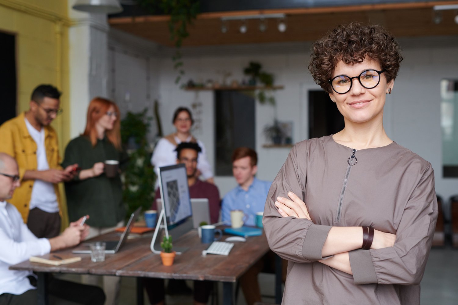 A confident professional in a busy, modern studio with her team working behind her
