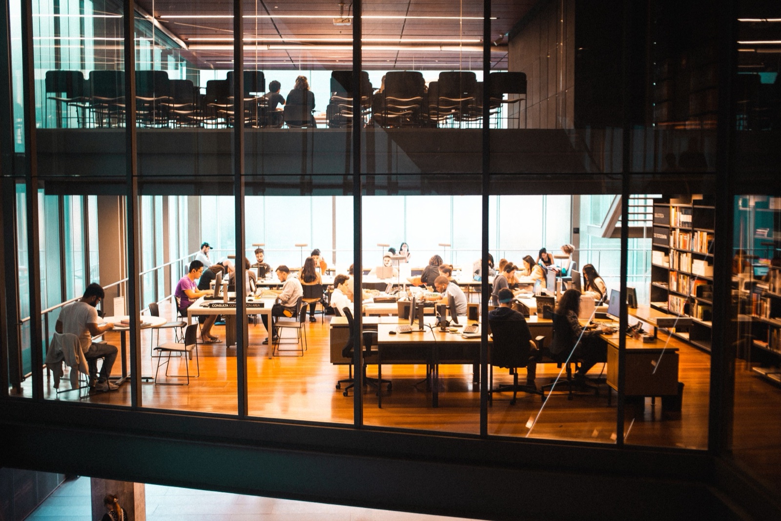 A busy team working together in a modern glass office at dusk