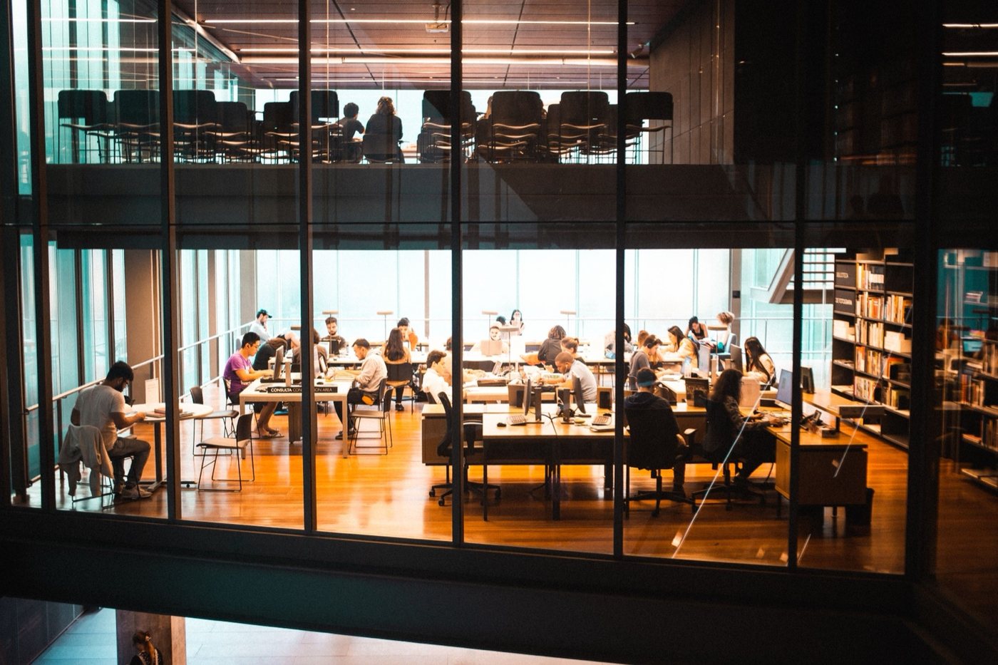 A busy team working together in a modern glass office at dusk
