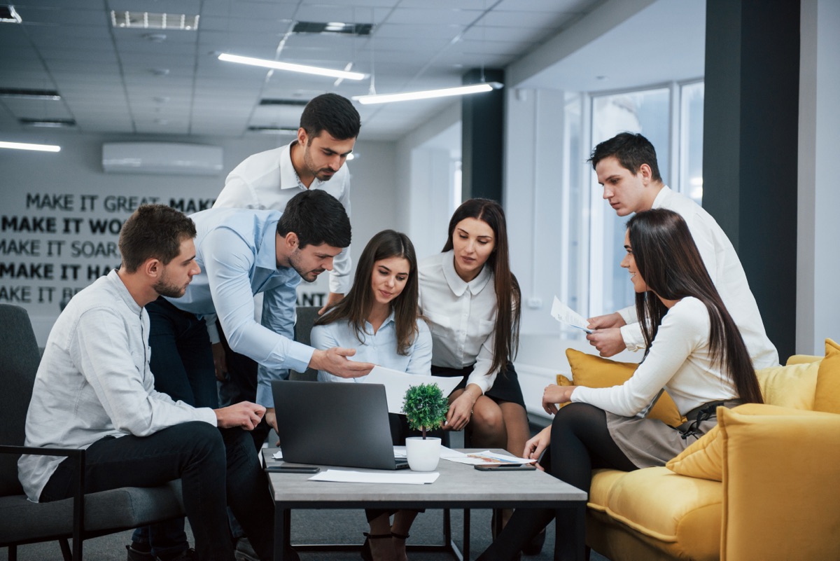 A team collaborating around a laptop in a modern office